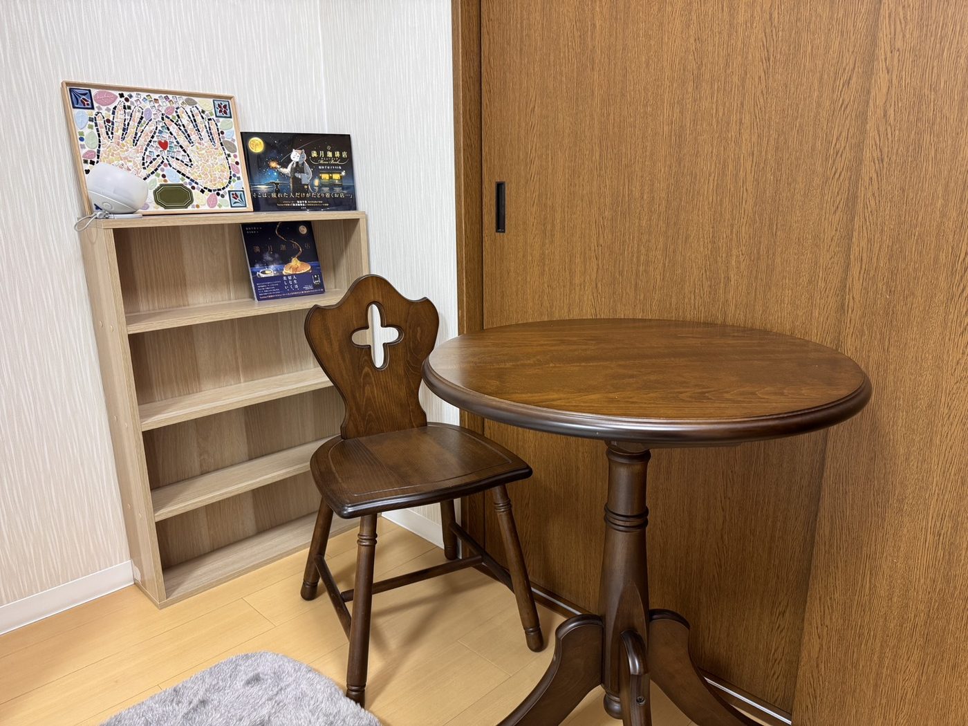 サロンの一角。本棚と、木の椅子と丸テーブル